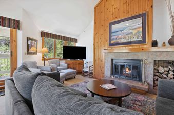 A living room in Kiva 428 features a fireplace with a roaring fire, a large couch, an armchair, and two end tables.