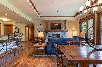 A living room with a fireplace, a couch, a coffee table, a dining table, and a window with an exterior view.