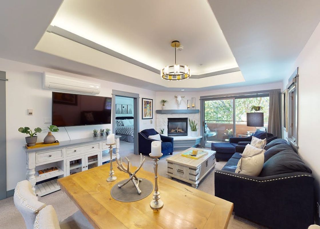 Bright living area in Canyon Creek B304 with dark blue sofas, a fireplace, and a dining table.