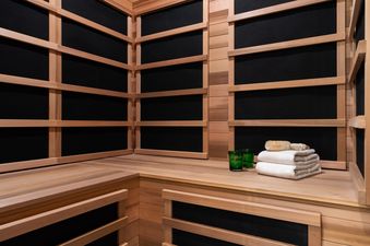 Infrared sauna at West Evergreen with wooden benches, towels, and spa accessories.