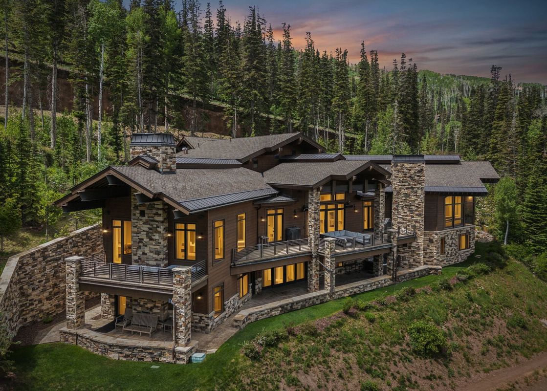 An aerial view of Grandview at The Colony, a luxury mountain home surrounded by pine trees during twilight.