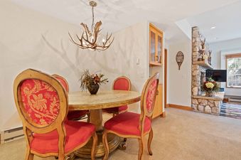 A dining area at The Charter C0105 featuring a round table with four red and gold upholstered chairs under an antler chandelier.