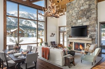The grand living space of Four Pines 102 features a fireplace, dining area, and stunning mountain views from large windows.