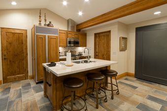 A well-appointed kitchen features warm wooden cabinetry, modern appliances, and a marble-topped island with seating, creating a functional and inviting space.