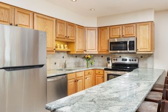 A modern kitchen at Montaneros 314 with stainless steel appliances, light wood cabinets, and granite countertops.