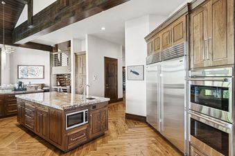 A luxury kitchen with natural wood cabinets, stainless steel appliances, and a granite-topped island at Grandview at The Colony.