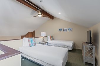 A secondary bedroom with two twin beds, a nightstand, and a TV, showcasing the comfortable and functional design of Snow Flower 127.