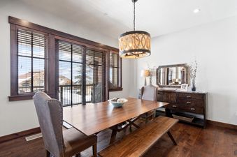 The dining area at Silver Star 33, featuring a large wooden table with chairs and a bench, illuminated by a decorative chandelier.
