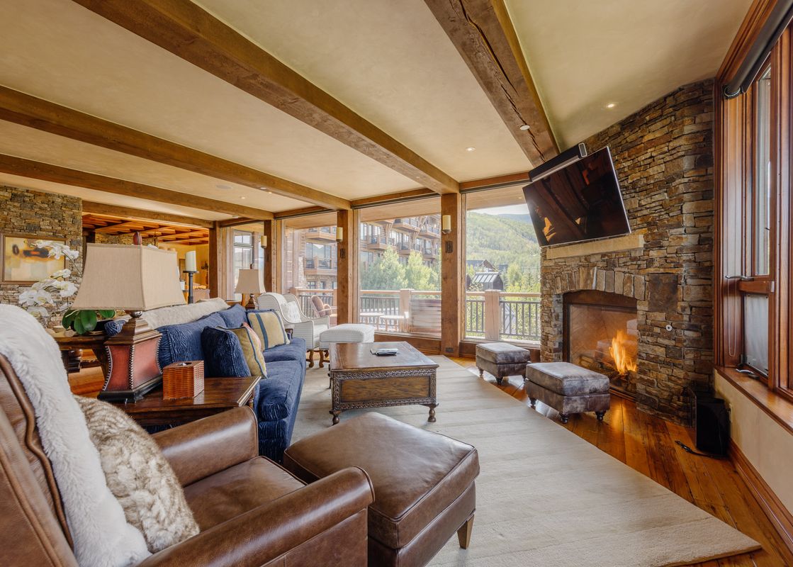 A cozy living room with a fireplace, comfortable seating, and large windows offering a view of the mountains.