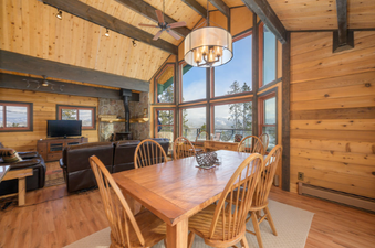 The dining area and living room of 273 Fallen Rock, showcasing an open-concept design with large windows.
