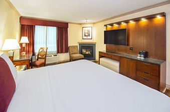 A Royal Canadian Lodge Premier Room with a king bed, fireplace, TV, and desk.