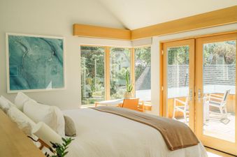 The master bedroom features a king bed with plush bedding and a large window with views of the forest.