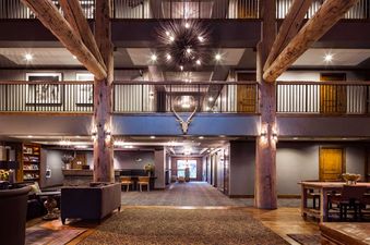 The multi-level grand lobby of Teton Mountain Lodge and Spa Lodge King featuring wooden pillars and a starburst chandelier.