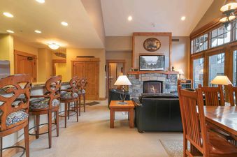A spacious living room with a fireplace and a large window with an outdoor view.