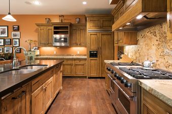 The gourmet kitchen in Silver Star 15 features wooden cabinetry, stainless steel appliances, and natural stone countertops.