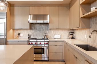 Modern kitchen in Moonlight Basin 80B Lodgeside featuring sleek appliances, light wood cabinetry, and a stylish tile backsplash.