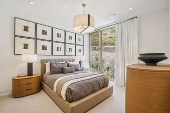 A well-appointed bedroom at Founders Place 1704 featuring a large bed, gallery wall art, and a large window overlooking scenic hills.