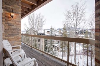 A private balcony at Chateau Chamonix CX333 overlooks a snowy landscape with trees and buildings under a winter sky.