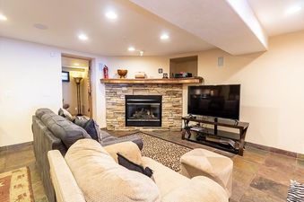 A cozy living room in 213 County Road 1041 with a stone fireplace, comfortable sofas, and a large flat-screen TV.