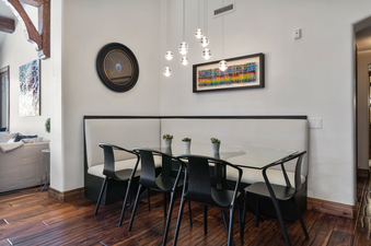Dining area in Grand Lodge Four Bedroom 302 with a white-cushioned banquette, black chairs, and a glass table.