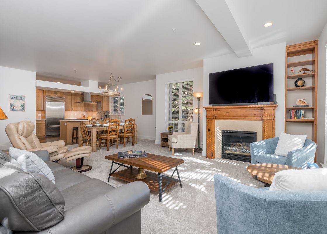 A spacious and inviting open concept living area at Snow Star 9 at Ketchum, featuring comfortable seating, a fireplace with a mounted TV, a full kitchen, and a dining area, all bathed in natural light.