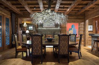 The dining room at Royal Wulff Lodge features a large wooden dining table surrounded by ornate chairs, set beneath a unique branch-like chandelier.