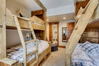 Bunk bedroom in The Lookout Home with light-wood bunk beds and view into an en-suite bathroom.