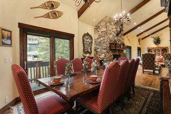 Dining room with a large wooden table and red upholstered chairs.