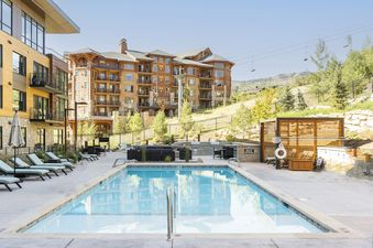 A swimming pool with lounge chairs and a view of a multi-level building in the background.