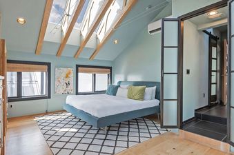 The primary bedroom features a dramatic vaulted ceiling and a doorway leading to the bathroom.