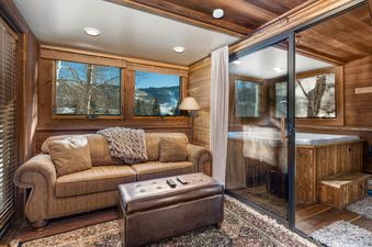 Deer Valley Delight features a cozy living area with a sofa, a leather ottoman and a view of the mountains.  The unit features a private hot tub.