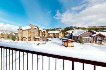 A beautiful view of the snowy landscape with buildings and mountains in the background, as seen from the balcony of Trailhead Lodge 821.