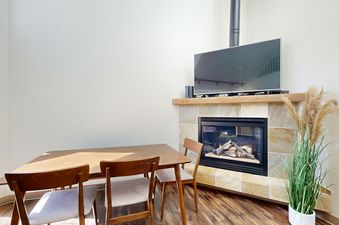 A living room with a fireplace, a dining table, and a flat screen TV.