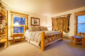 Cozy rustic bedroom in Kutuk 112 with a king-sized log frame bed and Western-themed decor.
