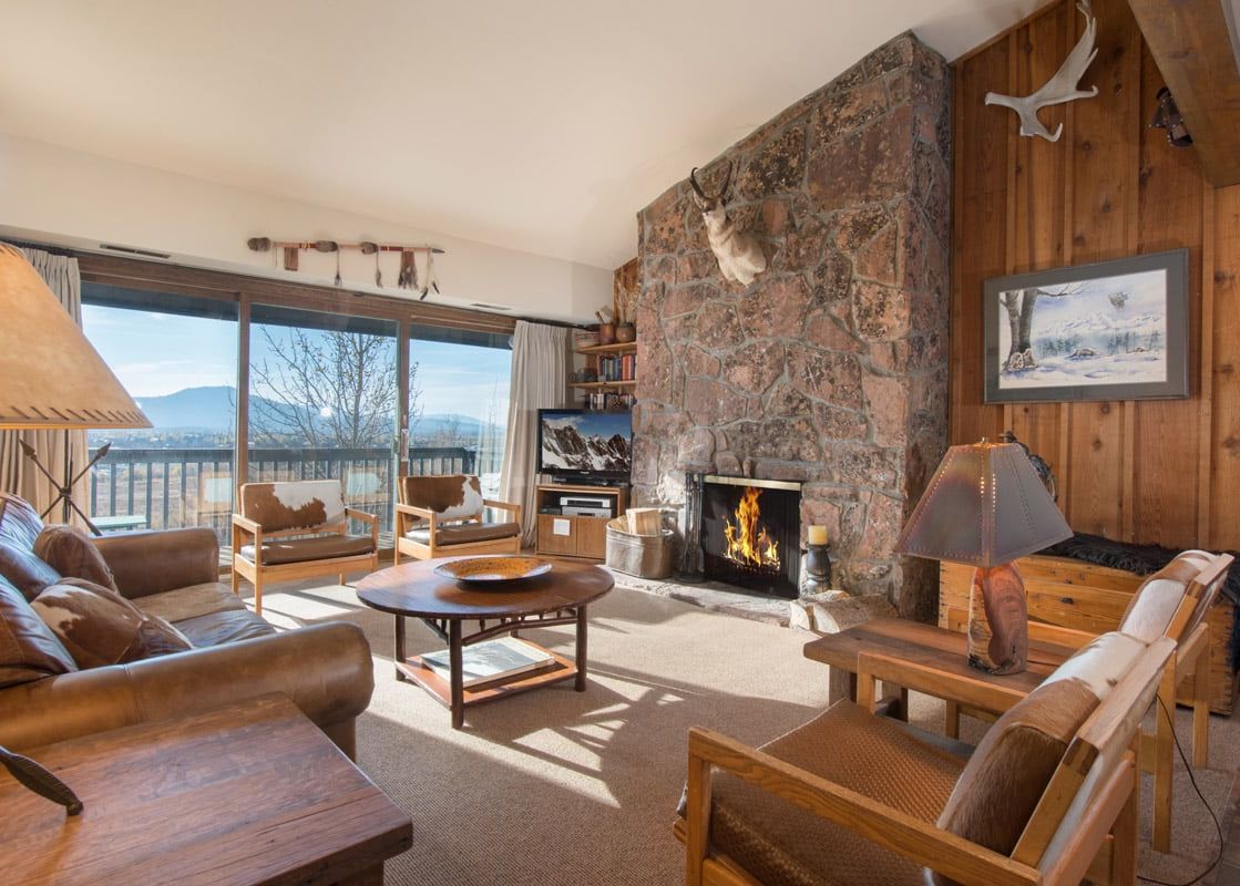 A cozy, mountain-style living room at Whiteridge A4 featuring a stone fireplace and scenic mountain views.