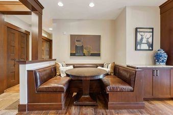 Enjoy a cozy meal in the dining nook of Empire Chalet at Flagstaff Lodge with a built-in bench, round table, and lovely artwork.