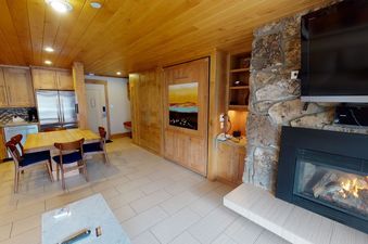 A modern living room with a fireplace, a flat screen TV, and a dining table with chairs.