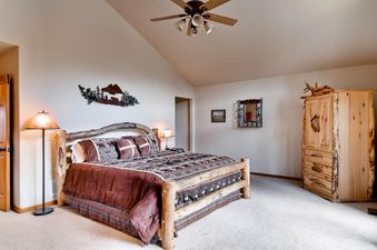 The bedroom at His High Place features a rustic wooden bed with patterned bedding, a ceiling fan, and wooden furniture, creating a cozy and natural ambiance.