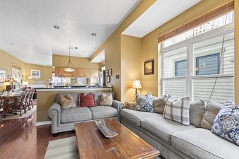 A bright and inviting living room at Old Town Retreat, featuring comfortable sofas, a wooden coffee table, and an open layout connecting to a dining area and kitchen.