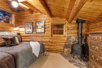 A cozy bedroom with a wood burning stove and a log cabin aesthetic.
