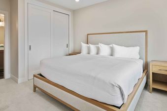 A modern, bright bedroom in SkyRidge 1307 with a king bed and an open view to the en-suite bathroom.
