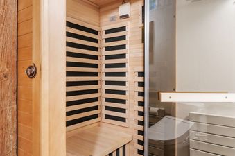 A modern private wooden infrared sauna with a glass door in the bathroom of Luxe Barnhouse.