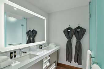 The bathroom in Quad Queen Bunk has two sinks, a large mirror, and a separate shower.
