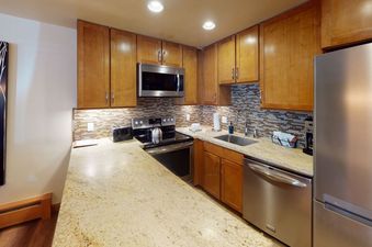 The kitchen in Manor Vail 112 has stainless steel appliances, granite countertops, and wood cabinets.
