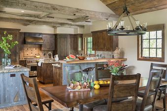 A rustic kitchen and dining area in Shooting Star Cabin 02 with dark wood cabinetry and a large dining table.