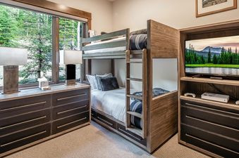 Moonlight Basin 4B Lodgeside bedroom with bunk beds, a television, and a dresser.