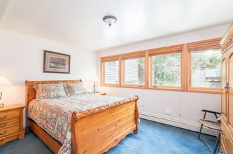 Cozy bedroom in Telluride Lodge 411 with a wooden bed and blue carpet.