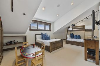 A spacious bedroom at Silver Horse at The Colony features two wooden beds, including a bunk bed, and a children's play table with chairs.