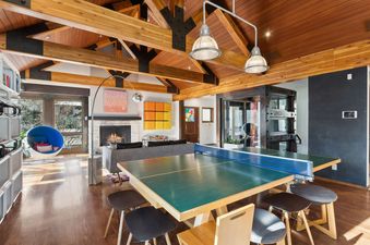 The living room in Town Lift Haven features a ping pong table, fireplace, and a retro hanging egg chair.