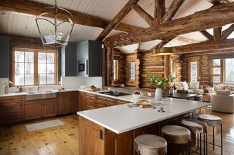 The open-concept kitchen and living area at Rodeo Ridge, featuring rustic log walls and modern white countertops.